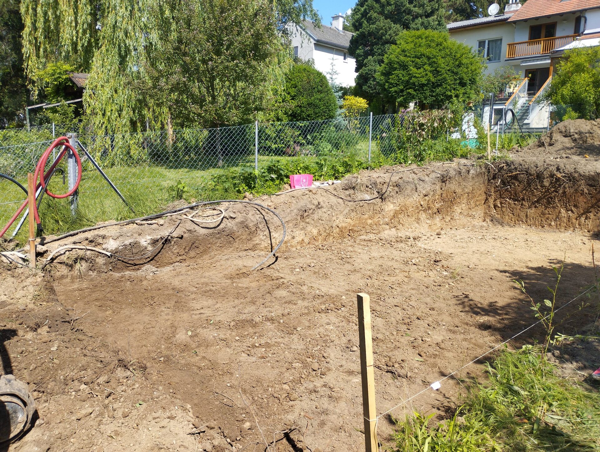 Minibagger beim Garten planieren im Bezirk Wiener Neustadt, der eine Fläche auf ein ebenes Planum abzieht