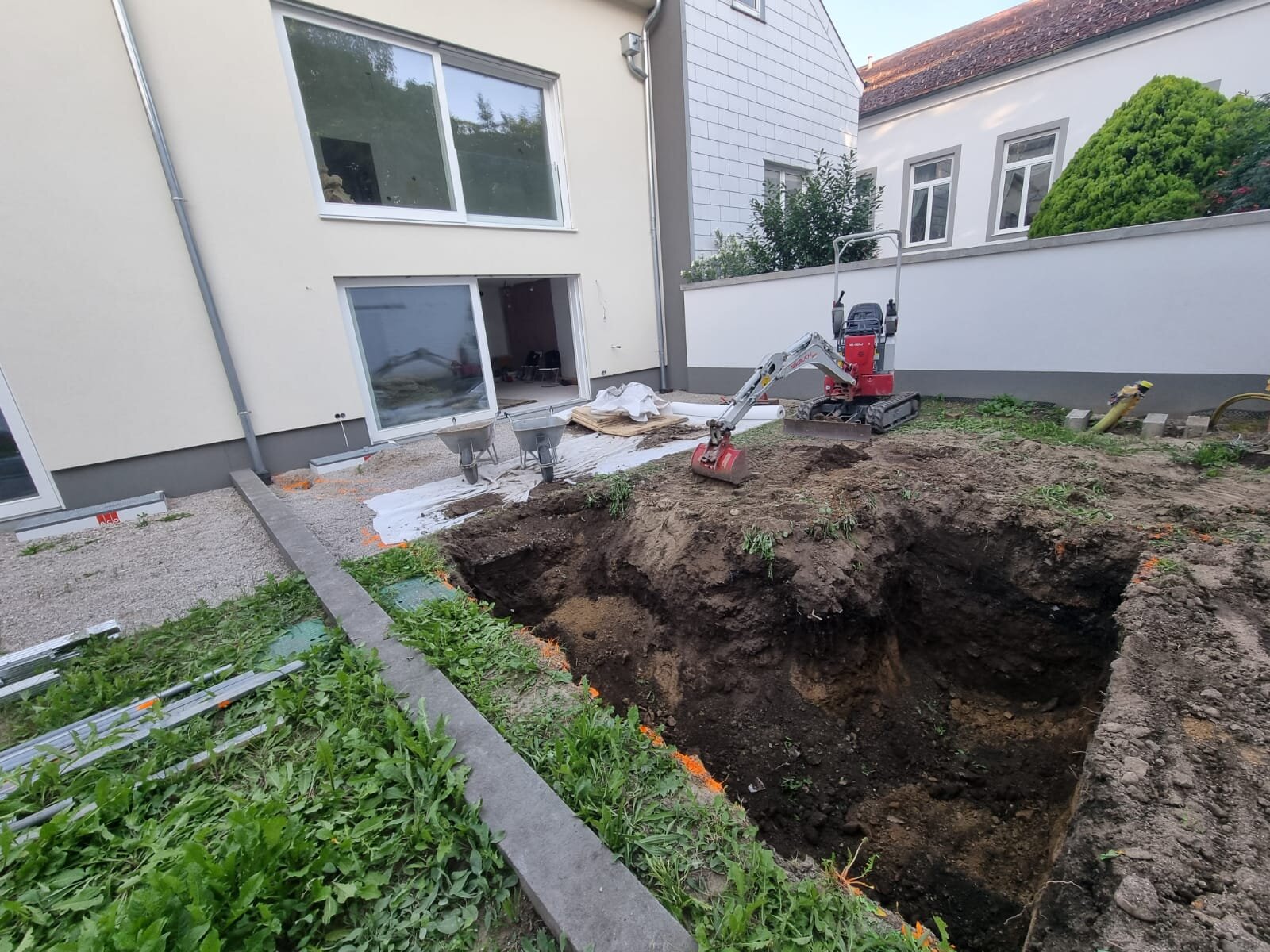 Minibagger nivelliert einen Garten im Bezirk Mödling und zieht den Boden mit Rotationslaser auf ein exakt waagrechtes Niveau ein