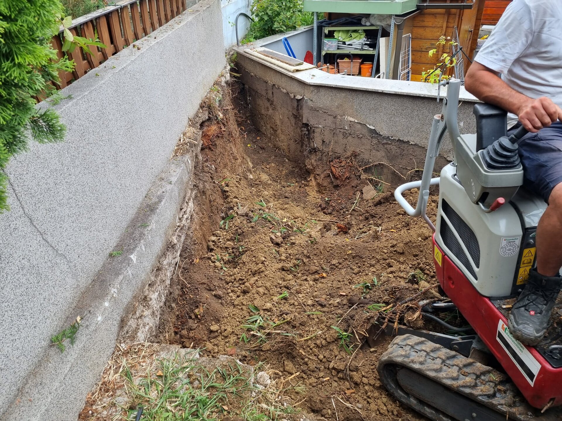 Minibagger formt eine Böschung beim Garten am Hang anlegen auf einem abschüssigen Grundstück im Bezirk Korneuburg