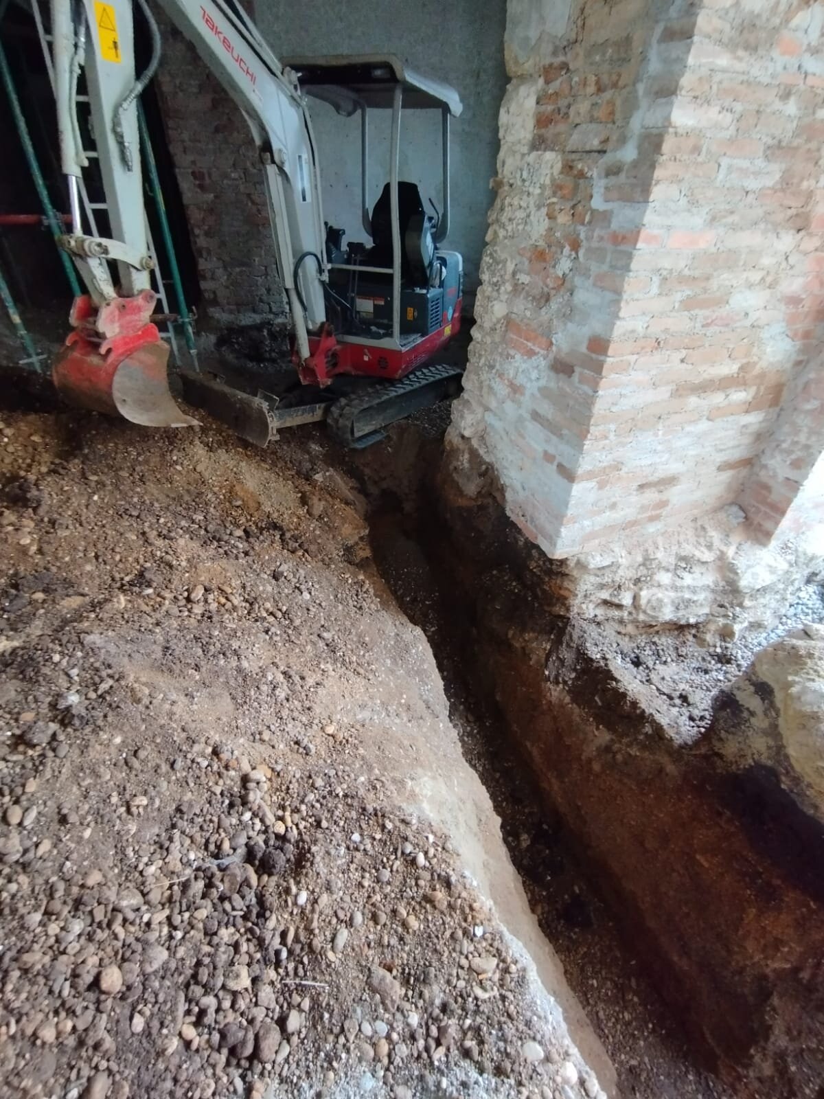 Minibagger trägt einen Hang ab und macht ein Hanggrundstück im Bezirk Hollabrunn eben, während die Fläche begradigt wird