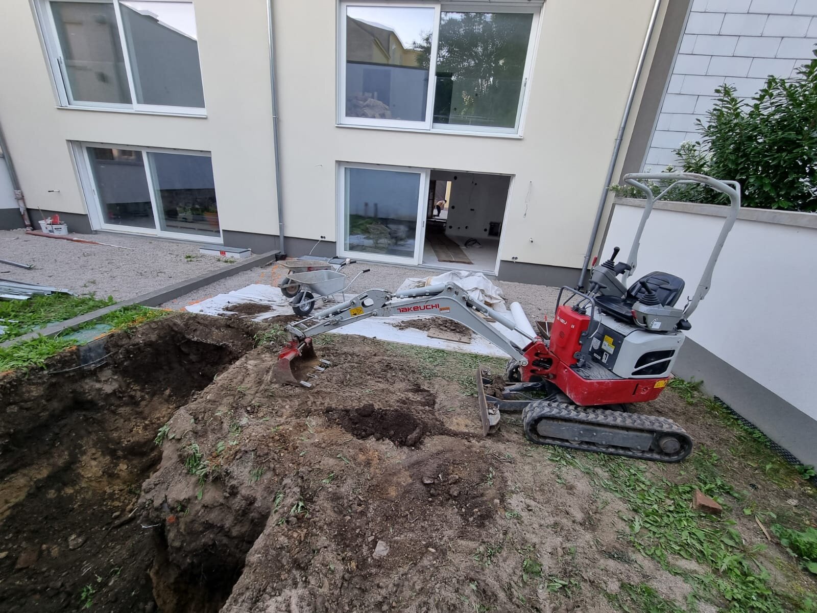 Minibagger trägt eine Böschung an einem Grundstück im Bezirk Tulln ab und flacht die Geländekante ab