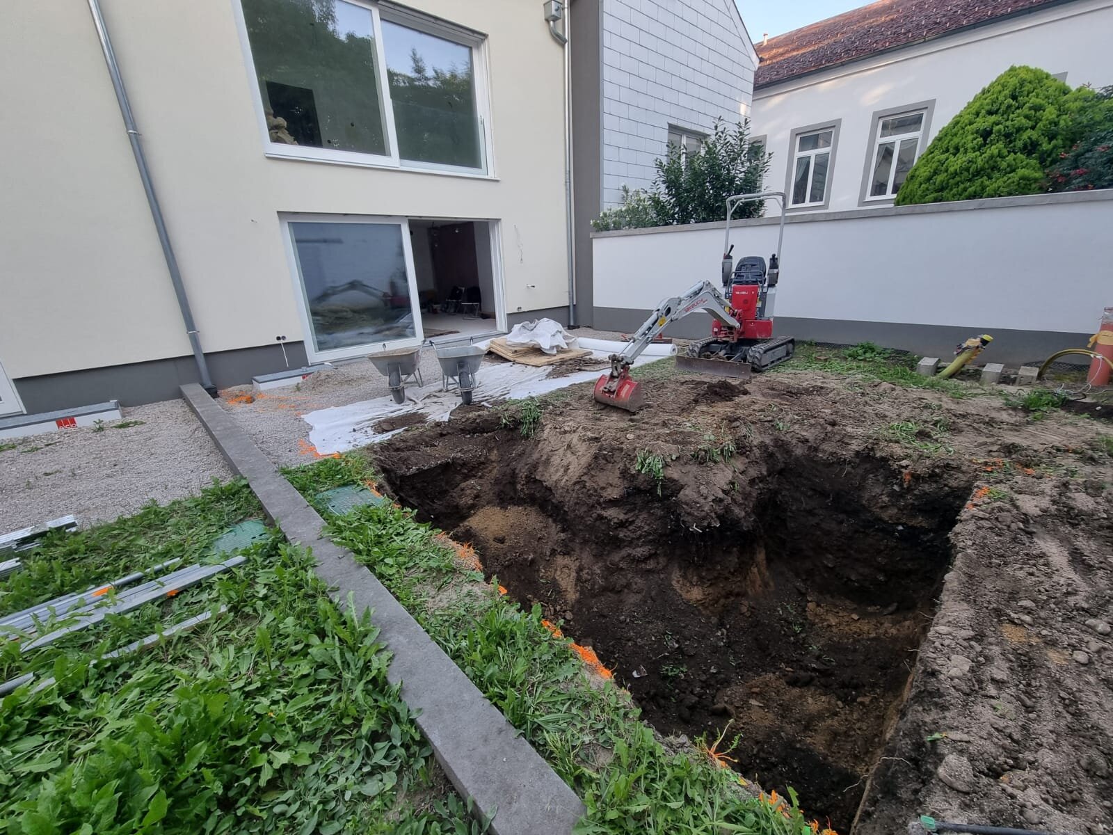 Minibagger terrassiert einen Hang im Bezirk Mistelbach und hebt mehrere Geländestufen aus, sodass ebene Absätze für einen Hanggarten entstehen