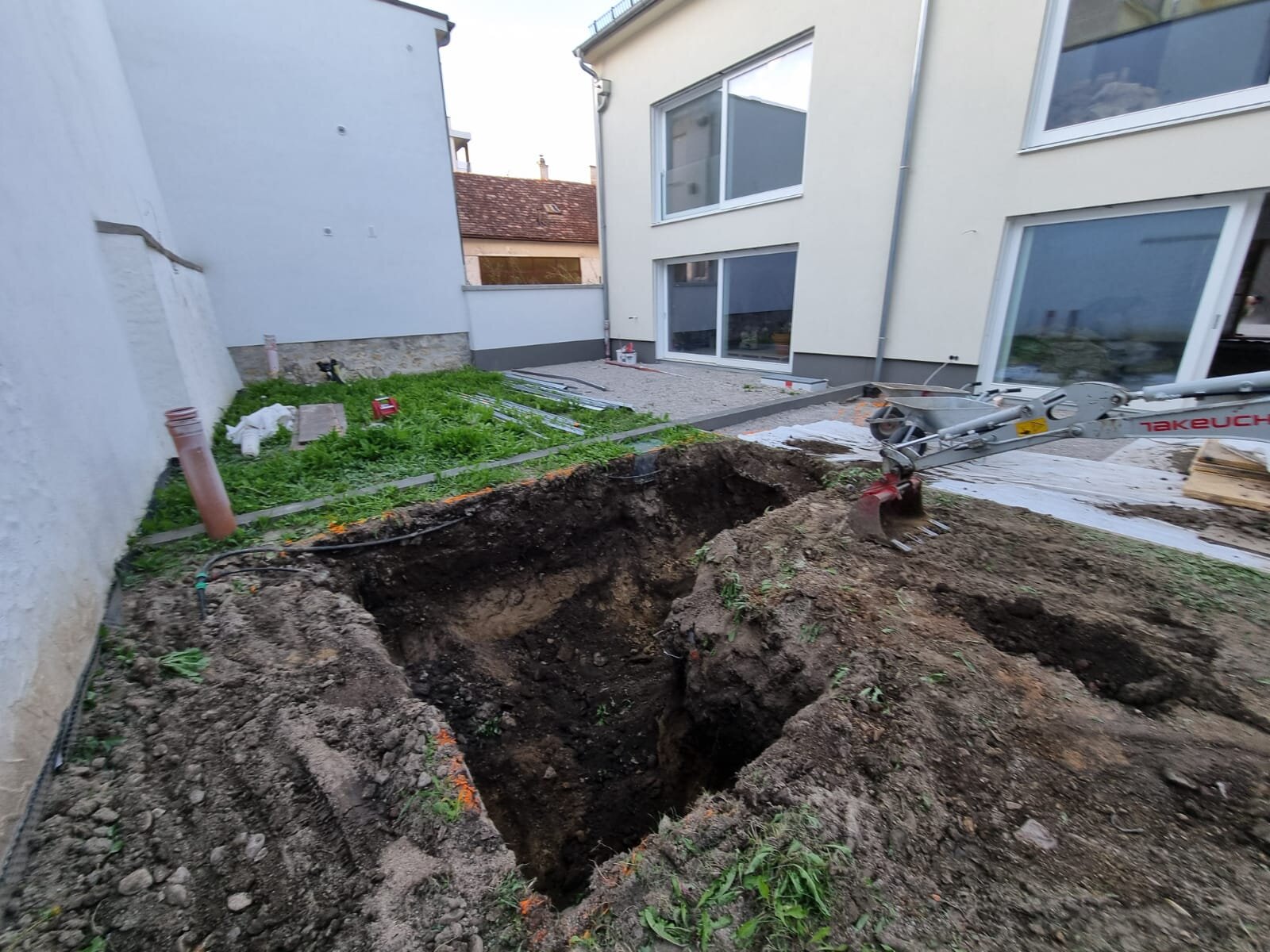 Minibagger flacht beim Hang abflachen im Bezirk Wiener Neustadt einen Steilhang ab und reduziert das Gefälle zu einer sanfteren, mähbaren Neigung