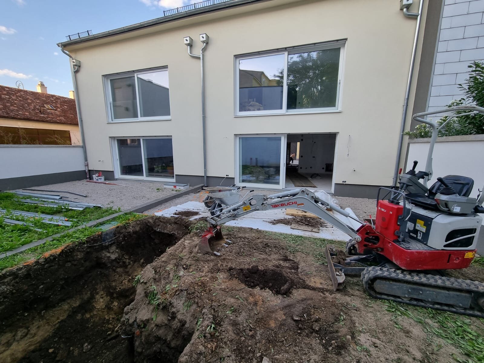 Minibagger glättet einen unebenen Rasen im Bezirk Gänserndorf und zieht die Oberfläche zu einem feinen Feinplanum ab