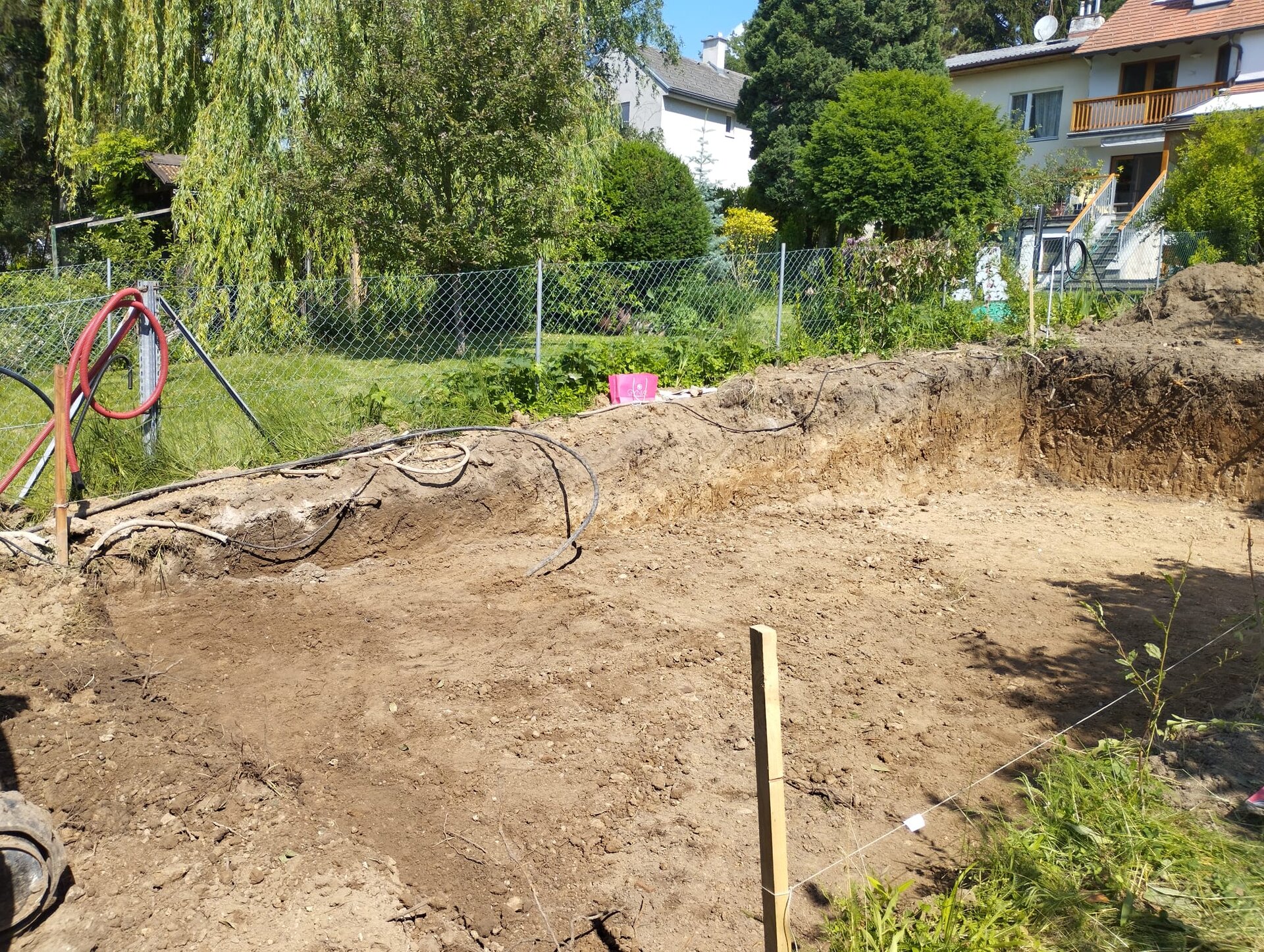 Minibagger bei den Aushubarbeiten am Hang auf einem abschüssigen Grundstück im Bezirk Mödling, Geländeeinschnitt für eine Baugrube