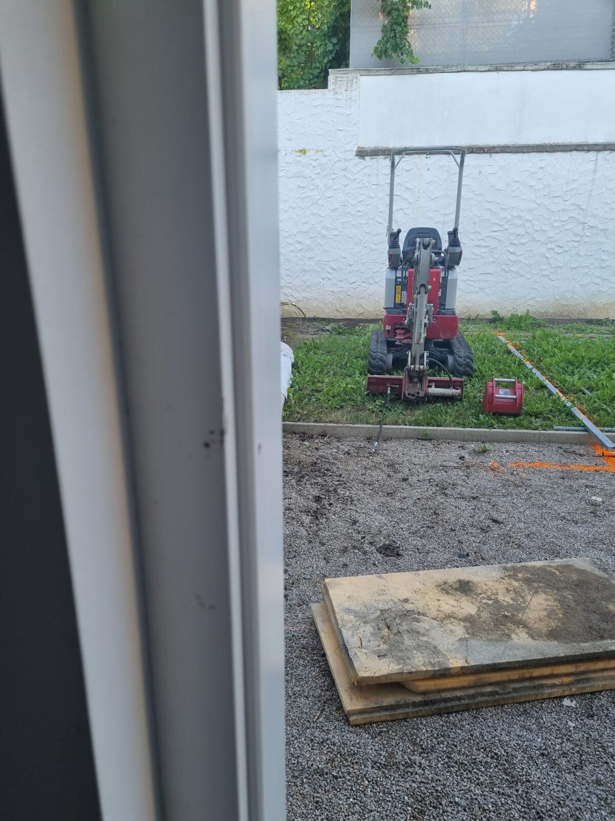Minibagger bei den Aushubarbeiten am Hang im Bezirk St. Pölten, der einen sauberen Einschnitt für eine Baugrube in Hanglage abträgt