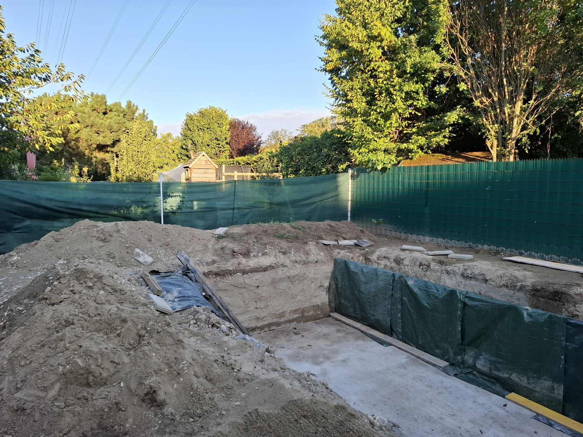 Bagger trägt beim Hang abtragen im Bezirk Baden einen steilen Hang stufenweise von oben ab und legt das Gelände für ebene Fläche tiefer